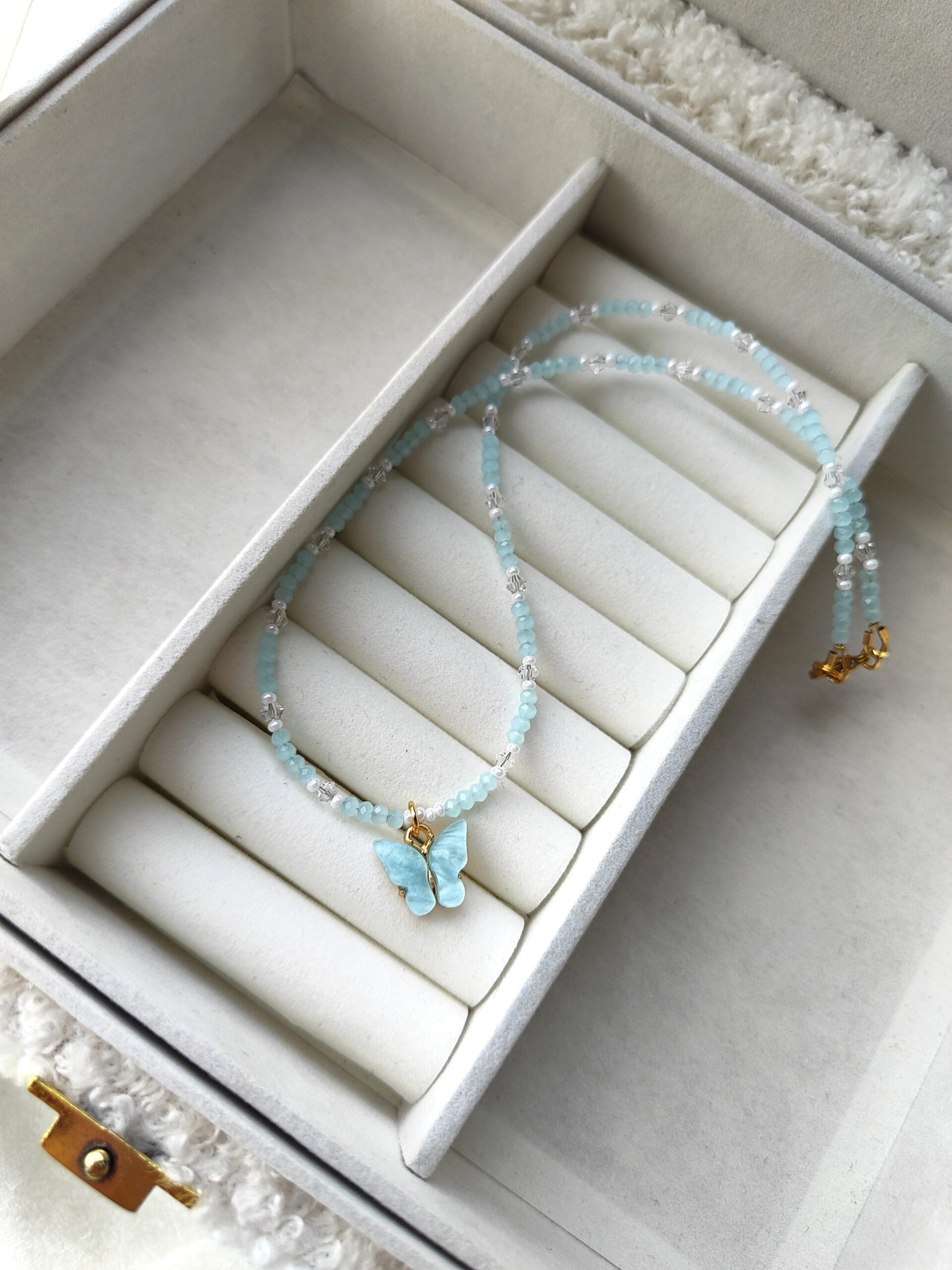 Žydros spalvos vėrinys su drugelio pakabuku