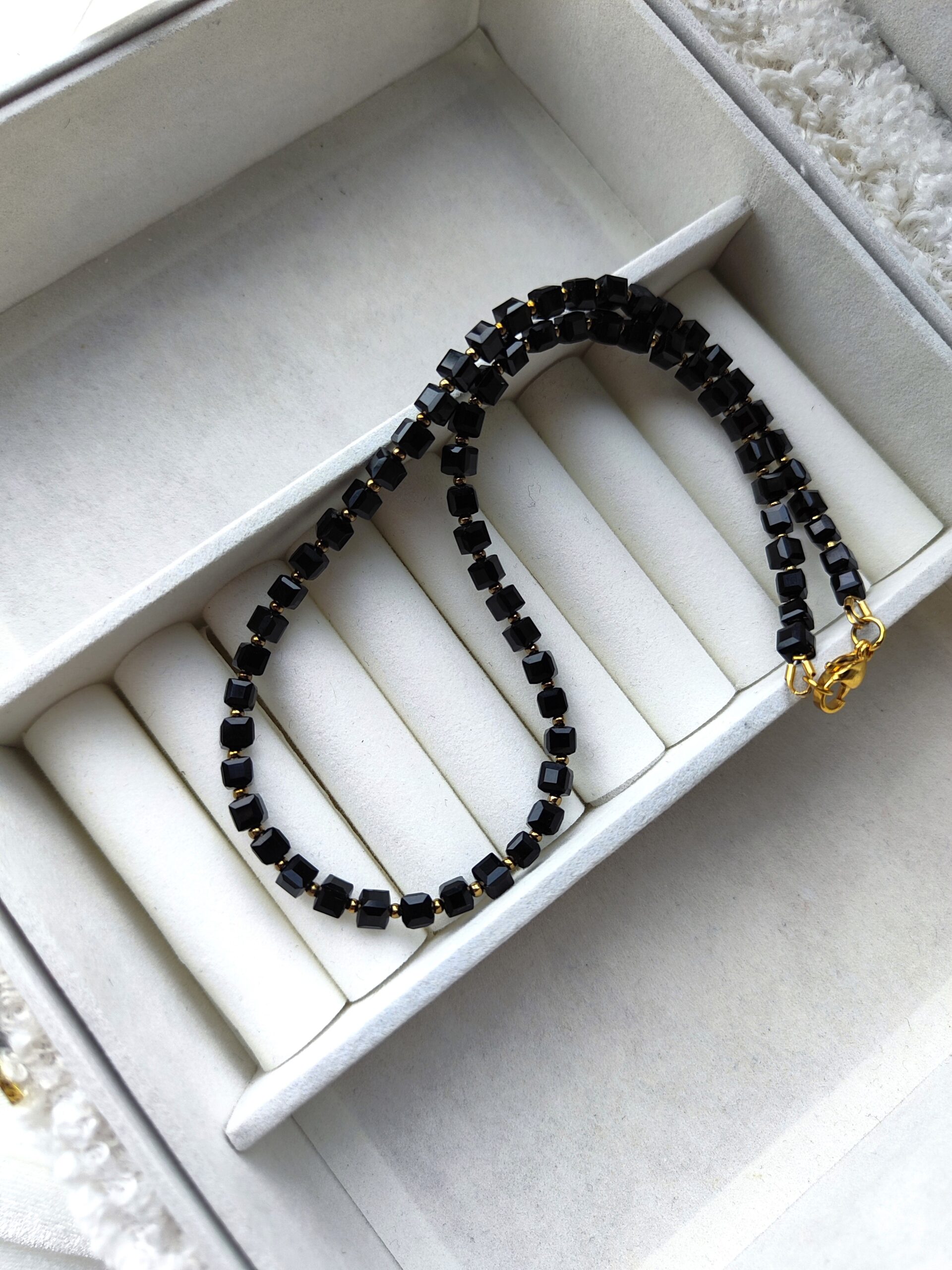 Juodo stiklo kubelių vėrinys